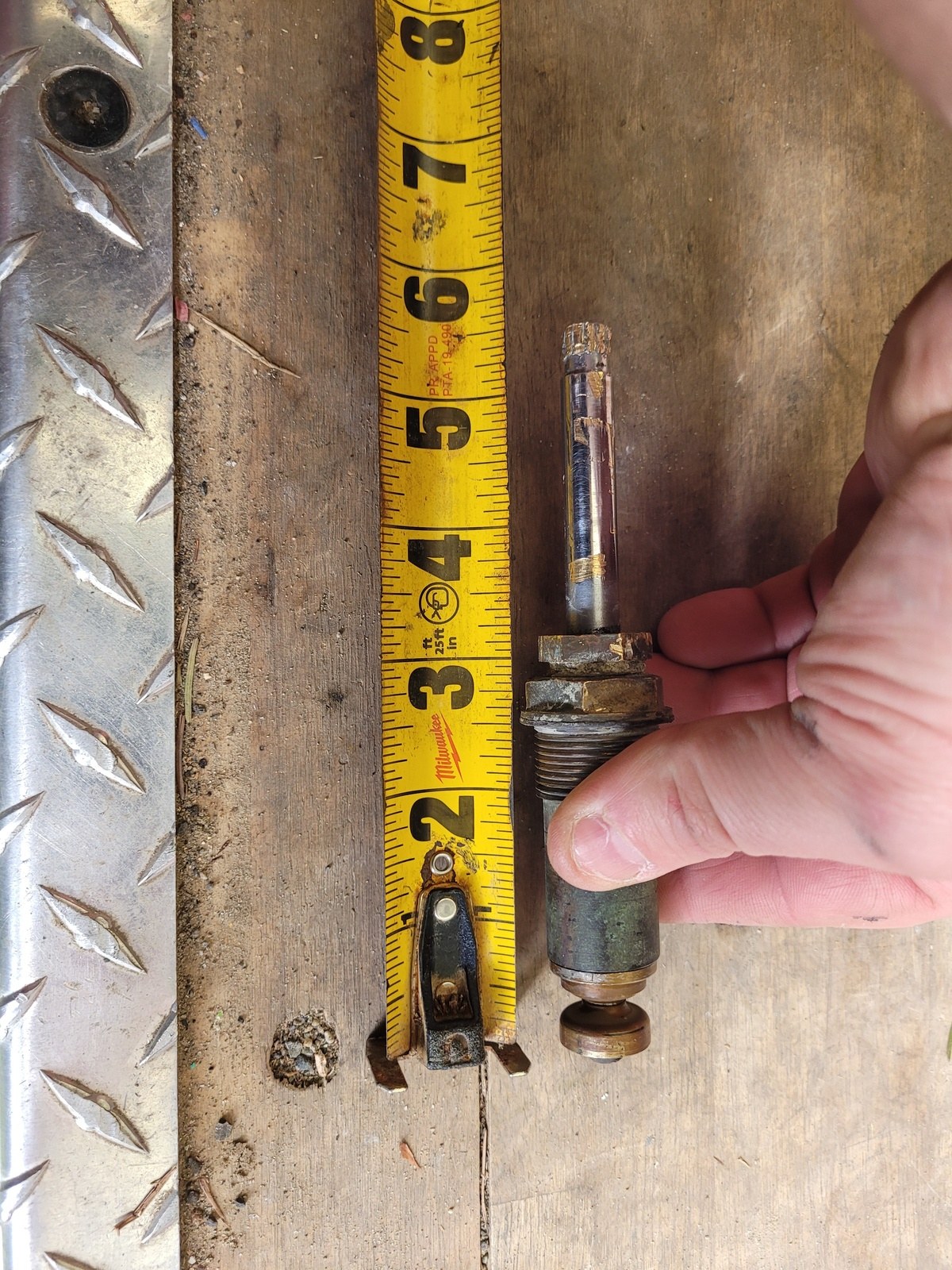 Corroded tub faucet stem held against a tape measure reading five and a half inches