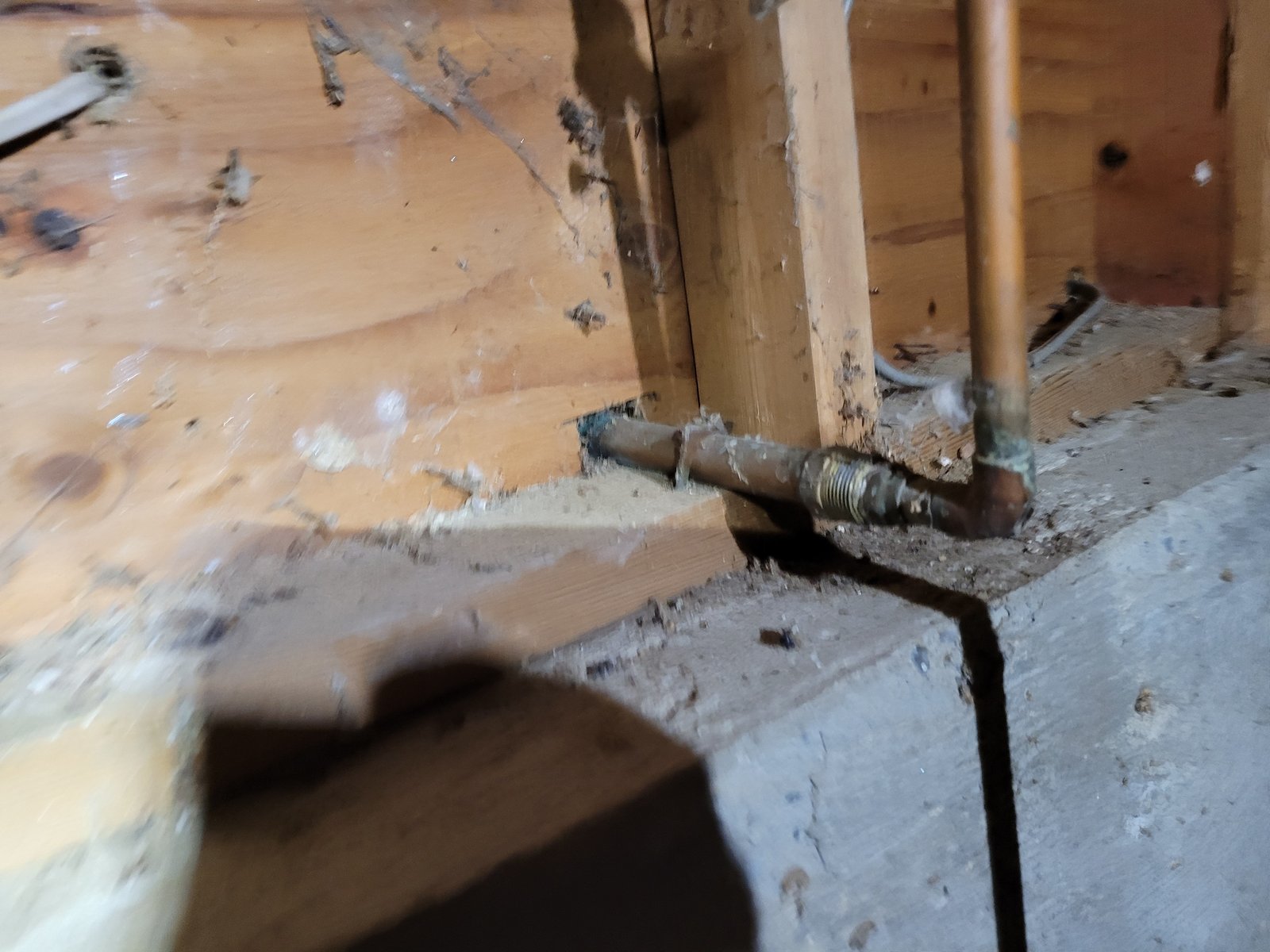 Corroded supply fitting at the mudsill in a Mukilteo crawlspace, with green patina on the copper elbow beside it