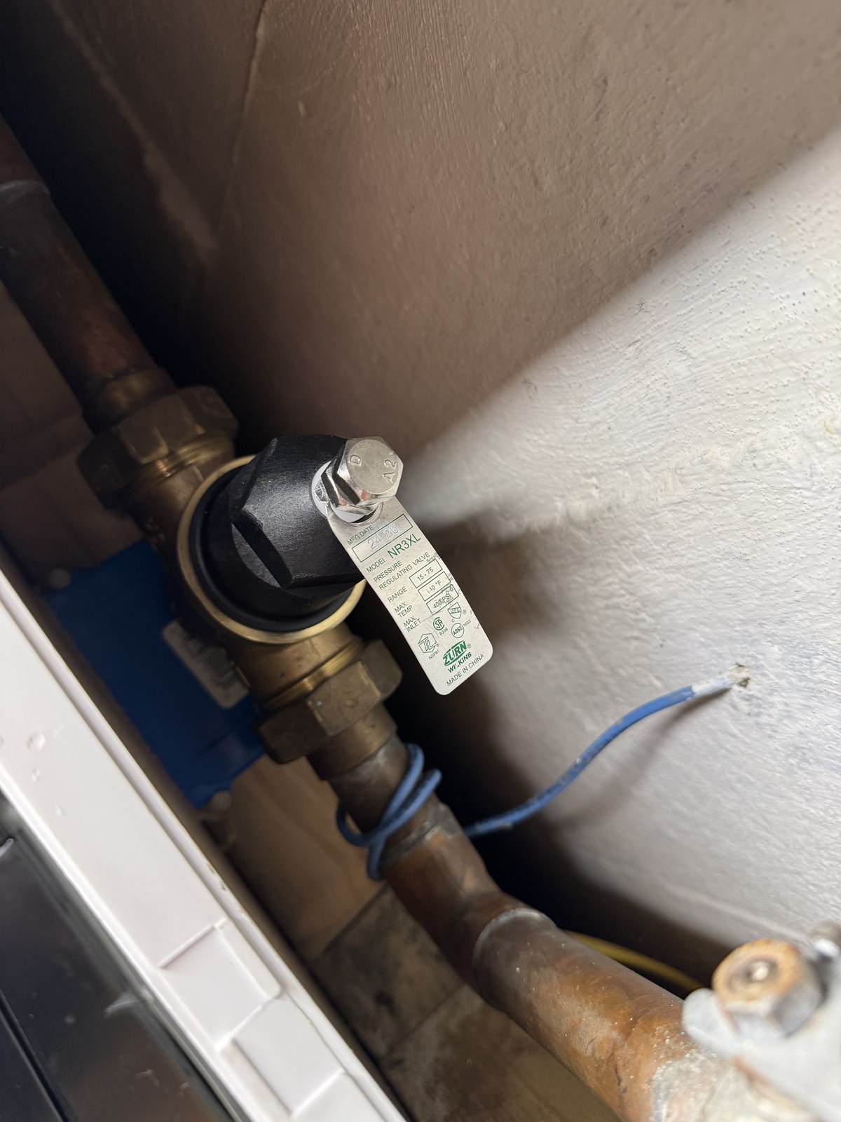 Zurn Wilkins pressure-regulating valve mounted on copper supply pipe with its rating tag still attached